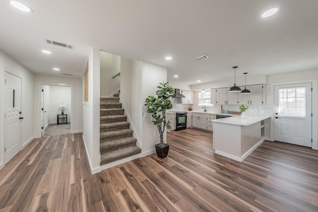 kitchen featuring white cabinetry, black electric range oven, sink, kitchen peninsula, and wall chimney exhaust hood