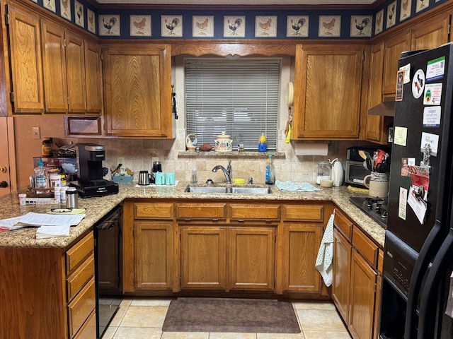 kitchen featuring sink, light tile patterned floors, light stone counters, and black appliances