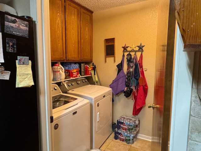 washroom featuring cabinets, washer and clothes dryer, light tile patterned floors, and a textured ceiling