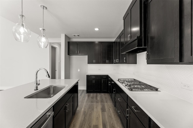 kitchen with sink, appliances with stainless steel finishes, hardwood / wood-style floors, hanging light fixtures, and decorative backsplash