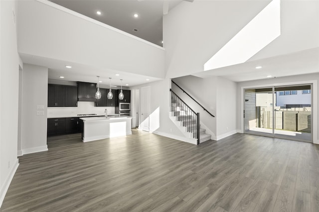 unfurnished living room featuring a towering ceiling, dark hardwood / wood-style flooring, and sink