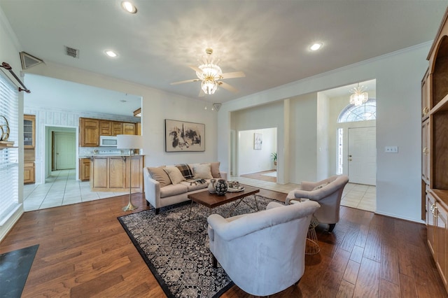 living area featuring light wood-type flooring, visible vents, crown molding, and recessed lighting