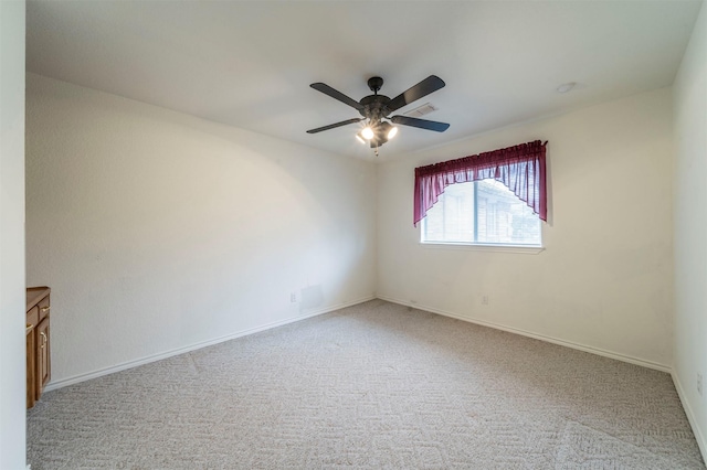 carpeted empty room featuring a ceiling fan, visible vents, and baseboards