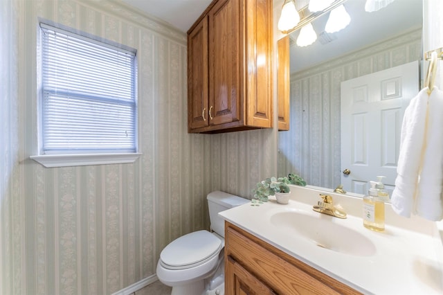 bathroom with vanity, toilet, and wallpapered walls