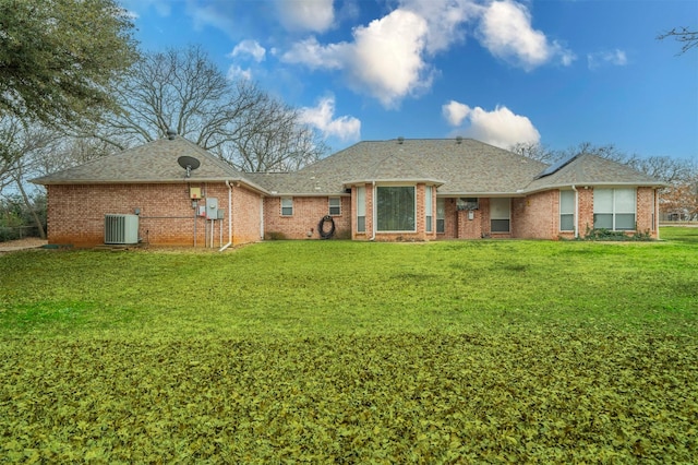 rear view of property featuring a shingled roof, a lawn, brick siding, and central air condition unit