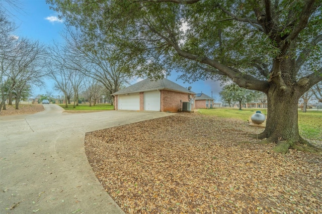 view of property exterior with an attached garage, central AC, concrete driveway, and brick siding