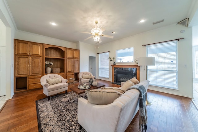 living room featuring ornamental molding, a premium fireplace, wood finished floors, and visible vents