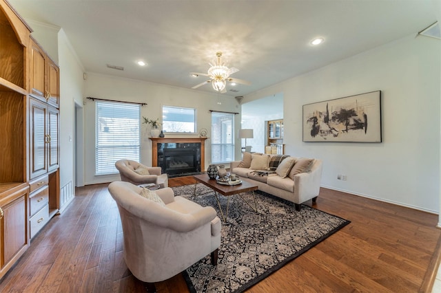 living area with a fireplace with flush hearth, ornamental molding, dark wood finished floors, and visible vents