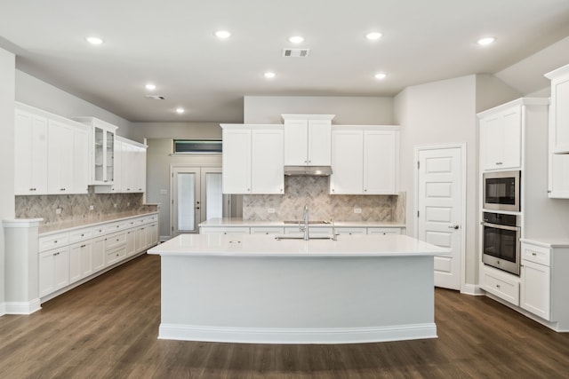 kitchen featuring white cabinetry, oven, sink, and a center island with sink