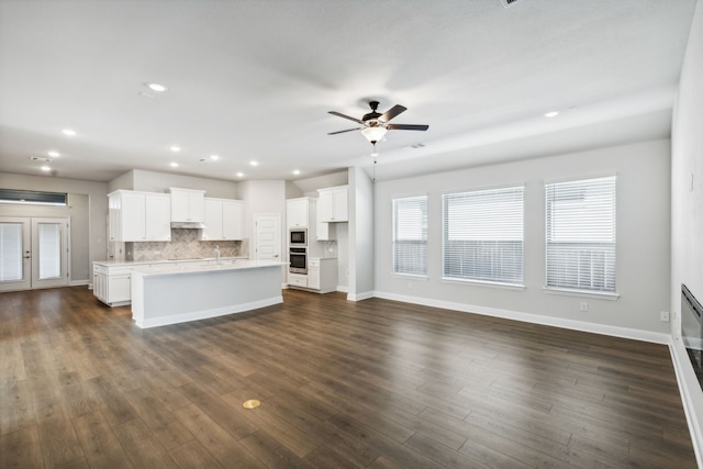 unfurnished living room with sink, dark wood-type flooring, and ceiling fan