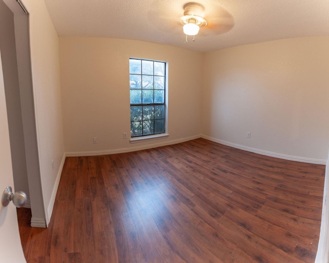 empty room with dark hardwood / wood-style flooring and a textured ceiling