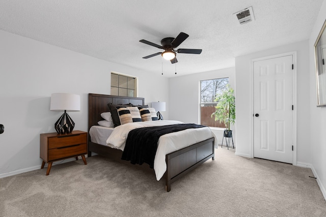 bedroom featuring light carpet, a textured ceiling, and ceiling fan