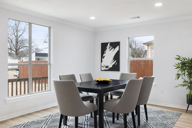 dining room featuring ornamental molding, light hardwood / wood-style floors, and a healthy amount of sunlight