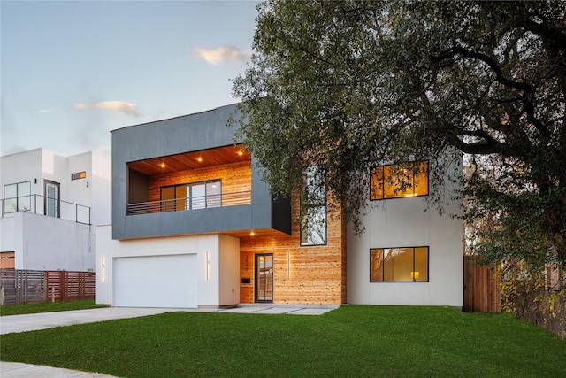 modern home featuring a garage, a front yard, and a balcony