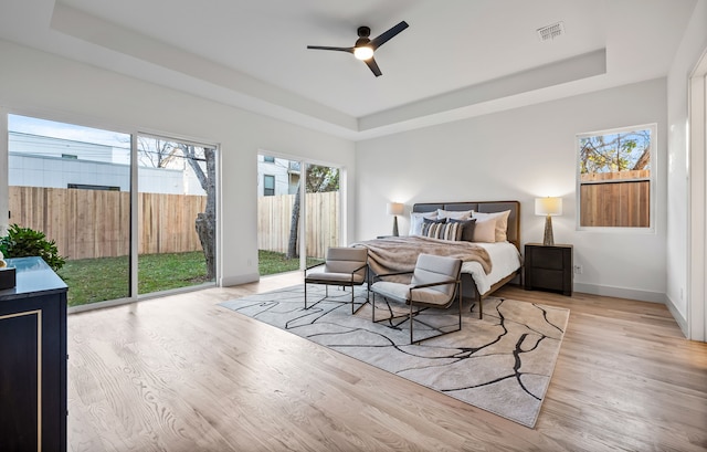 bedroom with a raised ceiling and light hardwood / wood-style floors