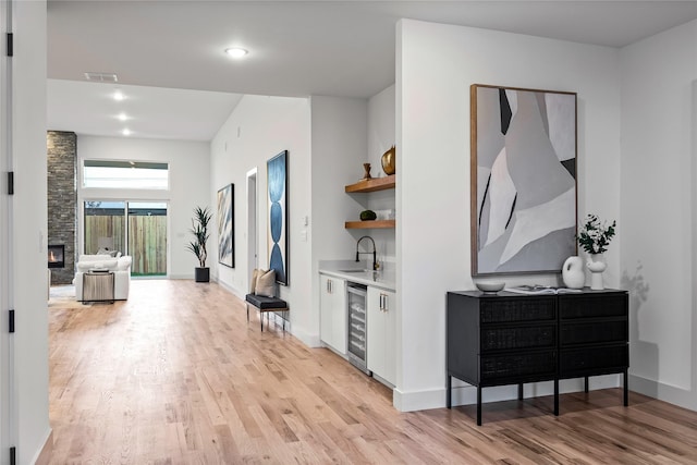 hallway with sink, wine cooler, and light hardwood / wood-style floors