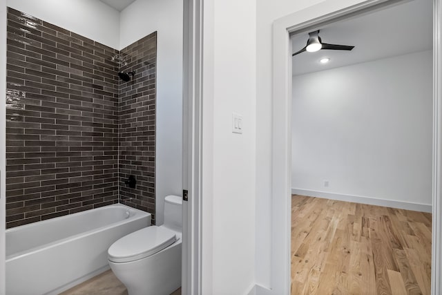 bathroom with tiled shower / bath combo, wood-type flooring, and toilet