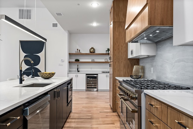 kitchen with premium range hood, appliances with stainless steel finishes, tasteful backsplash, sink, and beverage cooler