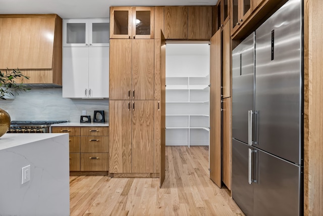 kitchen with white cabinetry, stainless steel built in fridge, light hardwood / wood-style floors, and tasteful backsplash