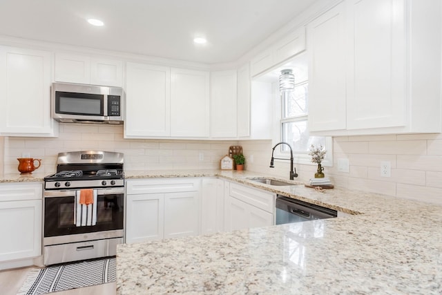 kitchen featuring white cabinetry, appliances with stainless steel finishes, sink, and light stone counters