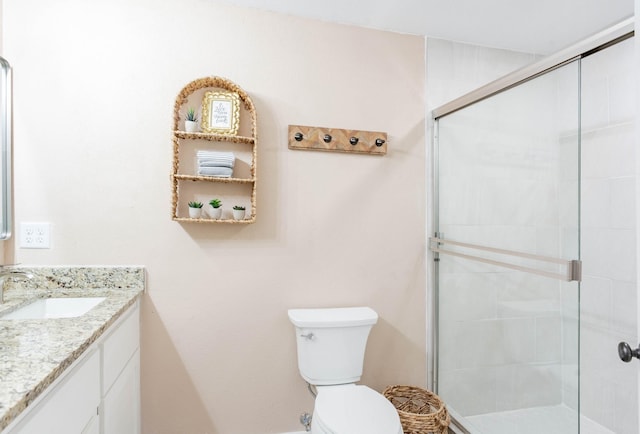 bathroom with vanity, a shower with shower door, and toilet