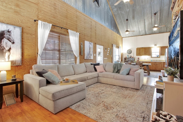 living room featuring ceiling fan, sink, light hardwood / wood-style floors, and high vaulted ceiling