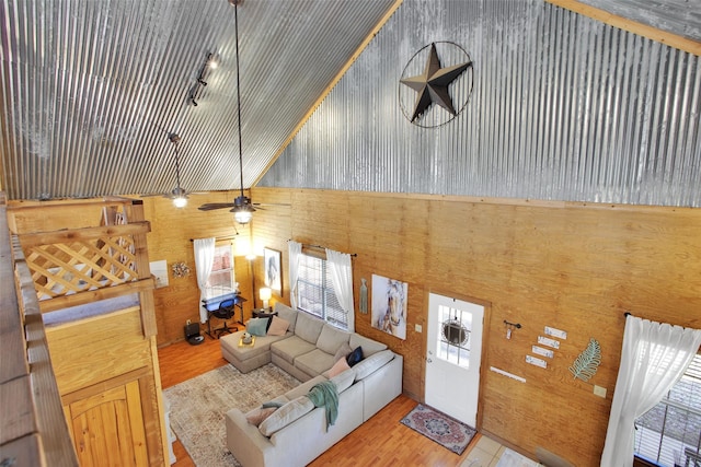 living room with a towering ceiling, wooden walls, and light hardwood / wood-style floors