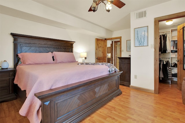 bedroom with light hardwood / wood-style floors, a spacious closet, ceiling fan, and a closet