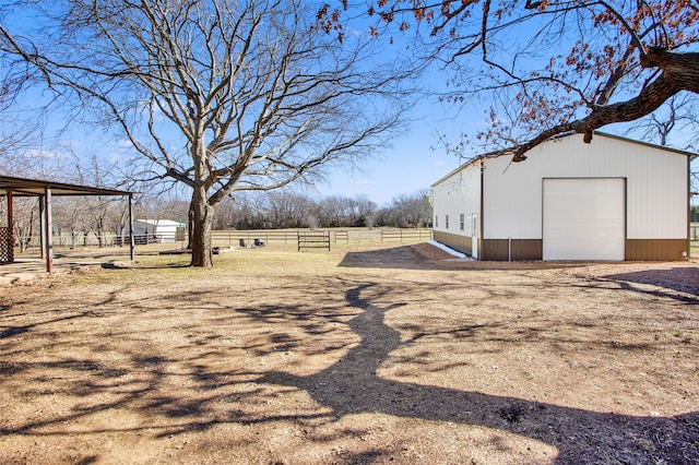 view of yard with a rural view, a garage, and an outdoor structure