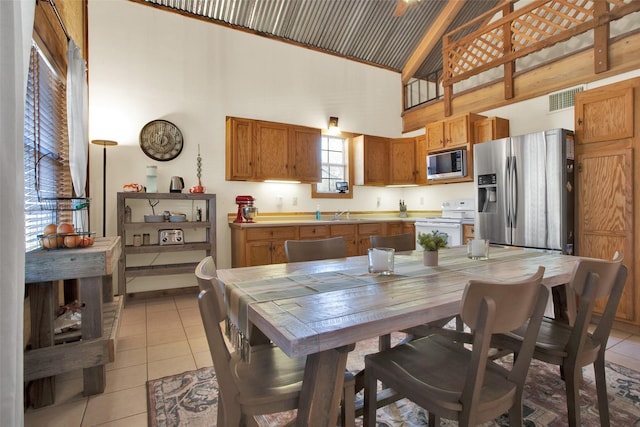 interior space featuring stainless steel appliances, light tile patterned floors, and high vaulted ceiling