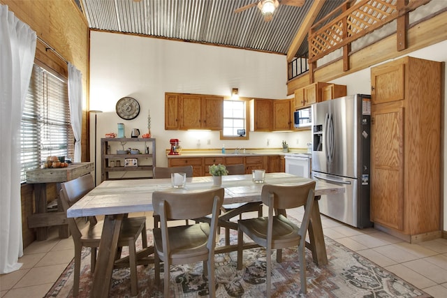 tiled dining space with ceiling fan, sink, and high vaulted ceiling