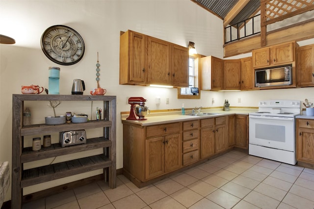 kitchen featuring stainless steel microwave, sink, light tile patterned floors, and white electric stove