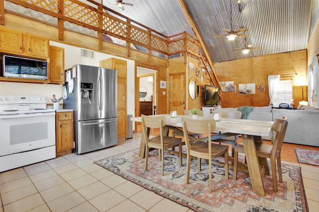 kitchen featuring built in microwave, white range with electric stovetop, wooden walls, and stainless steel refrigerator with ice dispenser