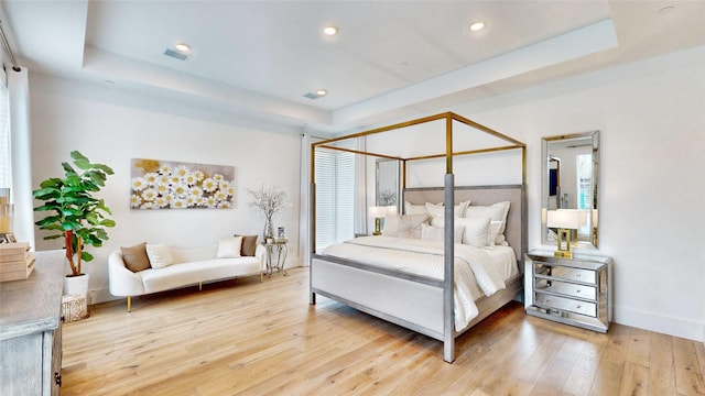 bedroom featuring a tray ceiling and light hardwood / wood-style flooring