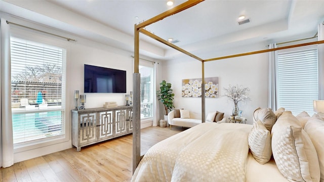 bedroom featuring light hardwood / wood-style floors and a raised ceiling