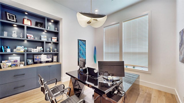 office with built in features and light hardwood / wood-style flooring