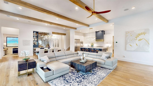 living room with beam ceiling, ceiling fan with notable chandelier, and light wood-type flooring