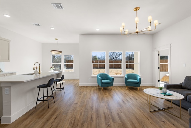 living room with an inviting chandelier, sink, and wood-type flooring