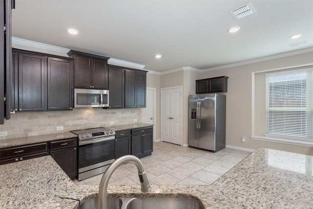 kitchen with appliances with stainless steel finishes, sink, light stone counters, and dark brown cabinetry