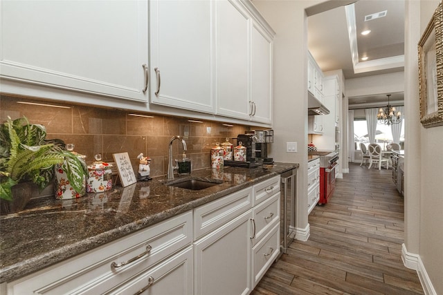 kitchen with sink, white cabinetry, stainless steel range, dark hardwood / wood-style flooring, and a raised ceiling