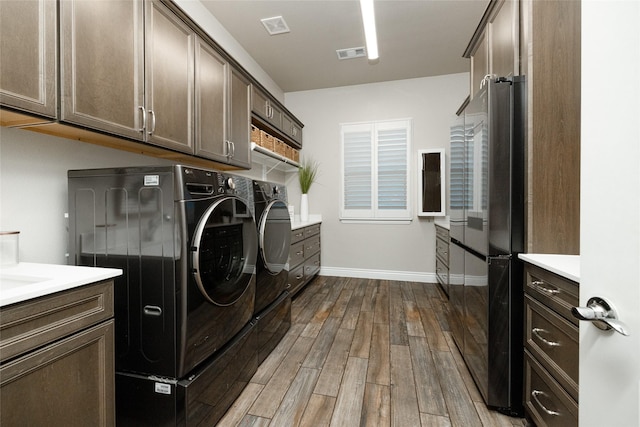 clothes washing area with cabinets, wood-type flooring, and washing machine and clothes dryer