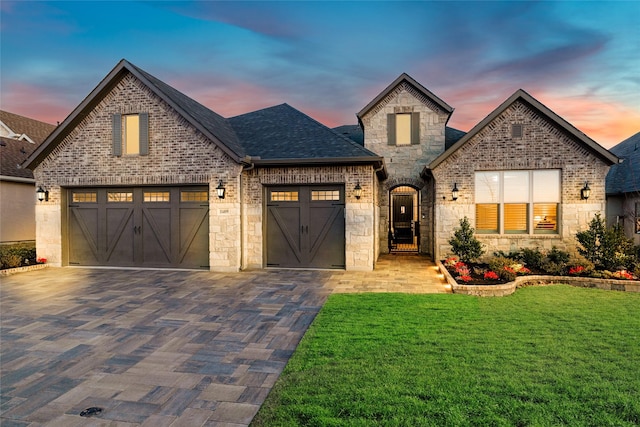 french country home featuring a garage and a lawn