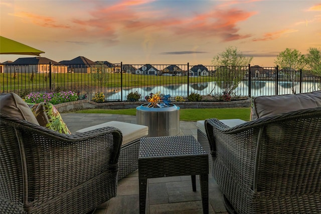 patio terrace at dusk with a water view and a fire pit