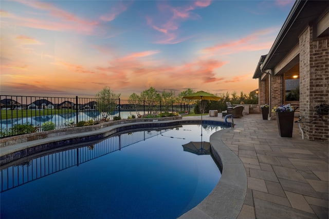 pool at dusk with a water view and a patio