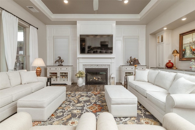 living room with dark hardwood / wood-style flooring, ornamental molding, a raised ceiling, and ceiling fan