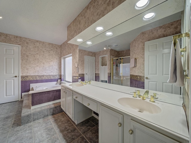 bathroom with a shower stall, double vanity, a sink, and wallpapered walls