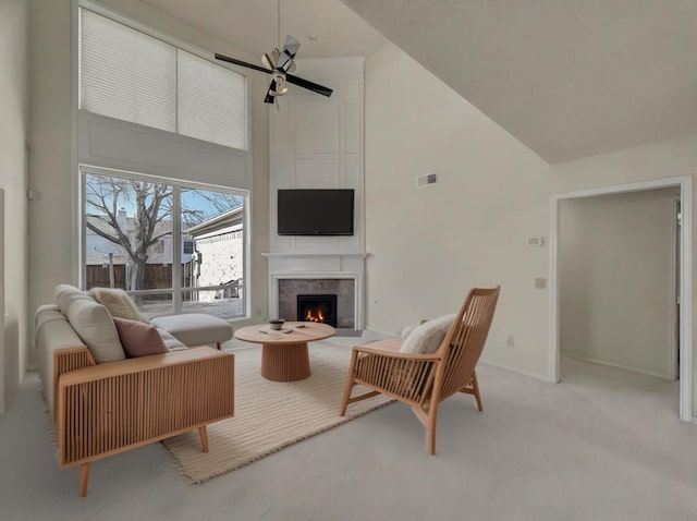 carpeted living area featuring ceiling fan, high vaulted ceiling, a premium fireplace, and visible vents