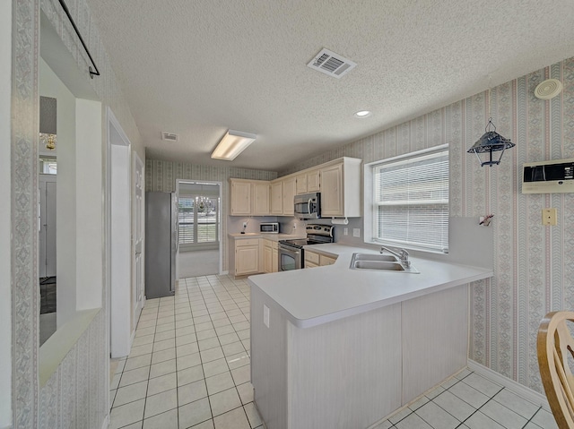 kitchen featuring light tile patterned floors, stainless steel appliances, a sink, light countertops, and wallpapered walls