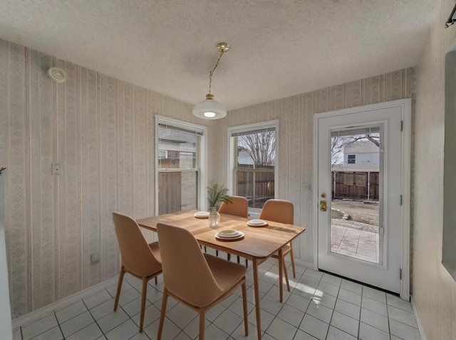 dining space featuring wallpapered walls, baseboards, a textured ceiling, and light tile patterned flooring