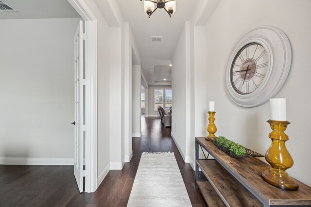 corridor with an inviting chandelier and dark hardwood / wood-style floors